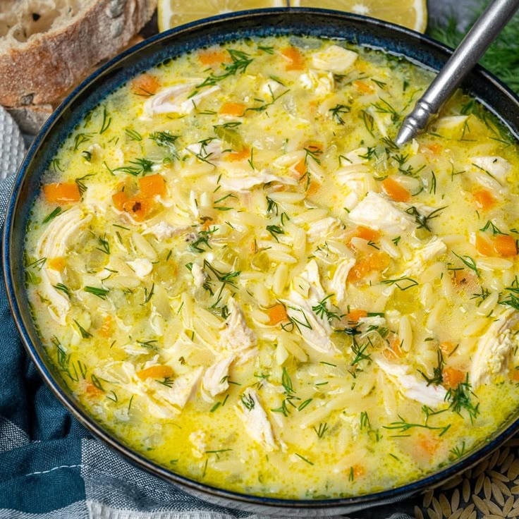 a bowl filled with chicken and carrots next to bread