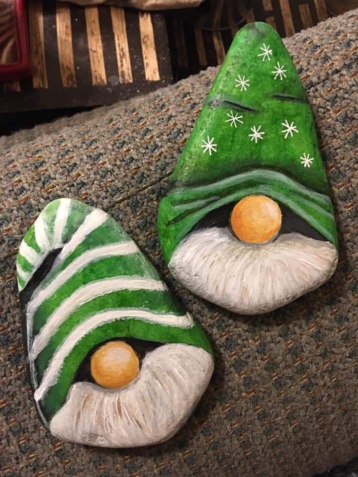 two green and white painted rocks sitting on top of a couch next to each other