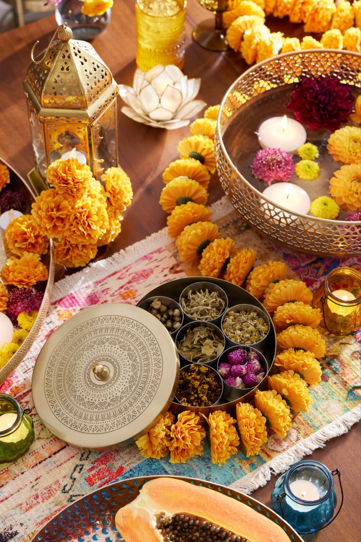 an assortment of food on a table with candles and other items in bowls around it