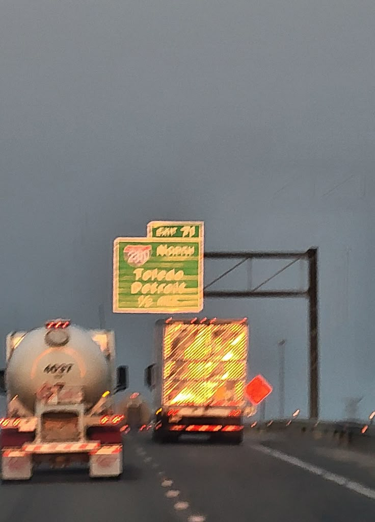 two tankers driving down the road with signs on them and traffic lights in the background