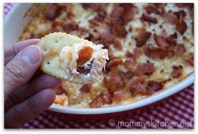 a hand holding a piece of food in front of a casserole dish with bacon on it