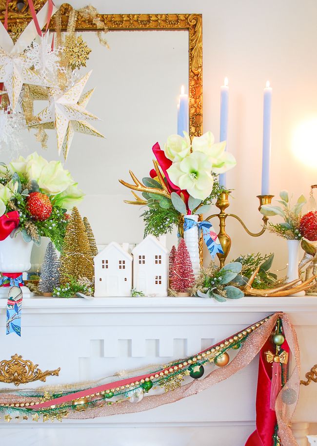 a mantel decorated with christmas decorations, candles and flowers on top of the mantle