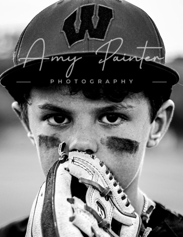 a young boy wearing a baseball hat and holding a catchers mitt to his mouth