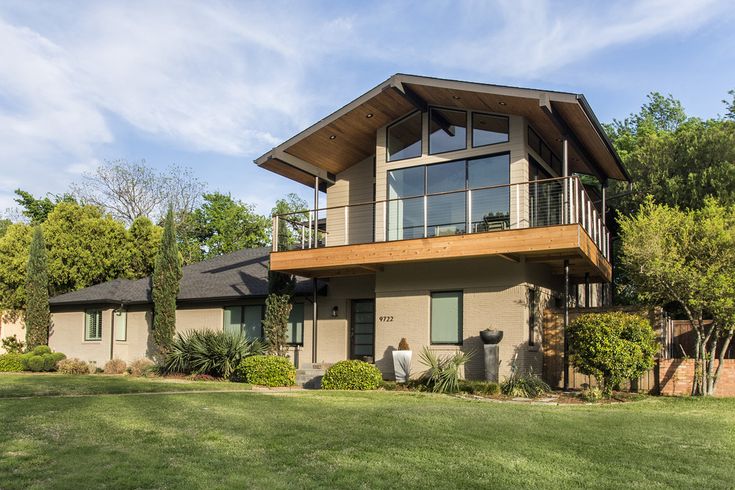 a two story house with a balcony on the second floor and green grass in front