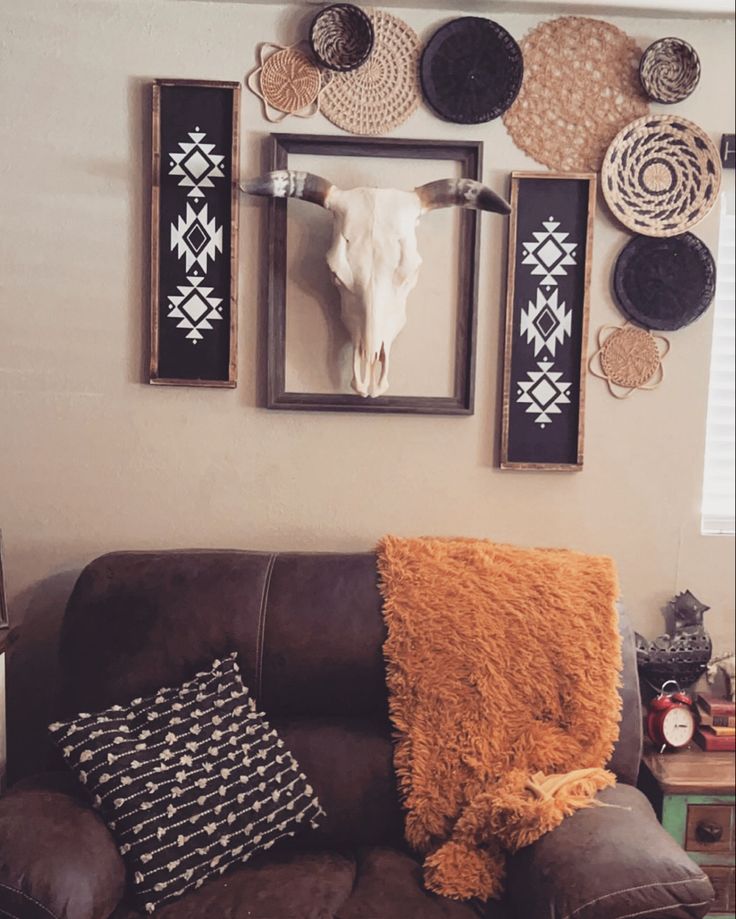 a living room with a brown couch and pictures on the wall above it, including a cow's head