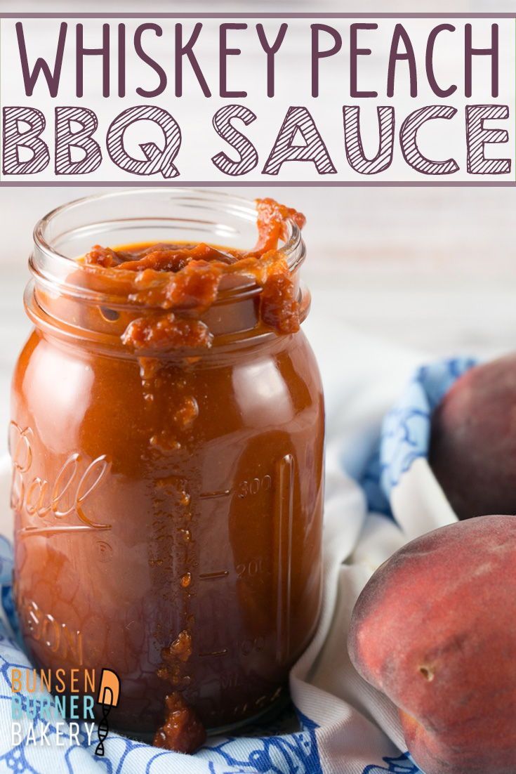 a glass jar filled with bbq sauce next to two peaches on a blue and white towel