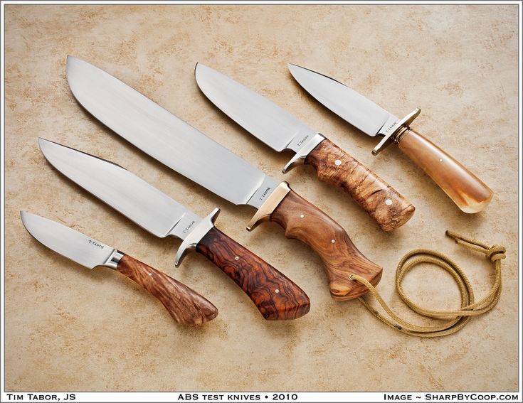 five knives are lined up next to each other on a table with a pair of scissors