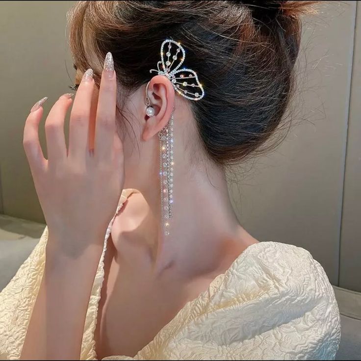 a woman with her hand on her face looking at herself in the mirror while wearing earrings