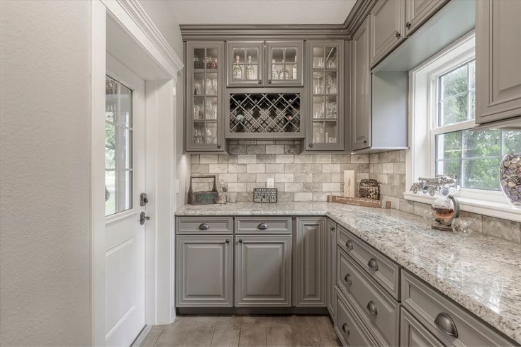 a kitchen with gray cabinets and marble counter tops