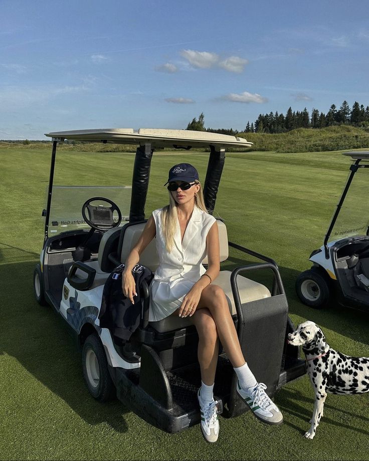 a woman sitting on top of a golf cart next to a dog