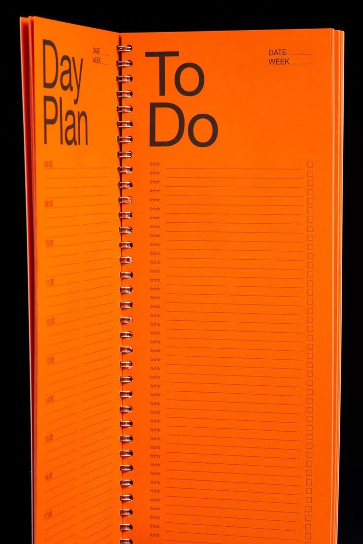 an orange spiral notebook with the words day plan to do written on it, in front of a black background