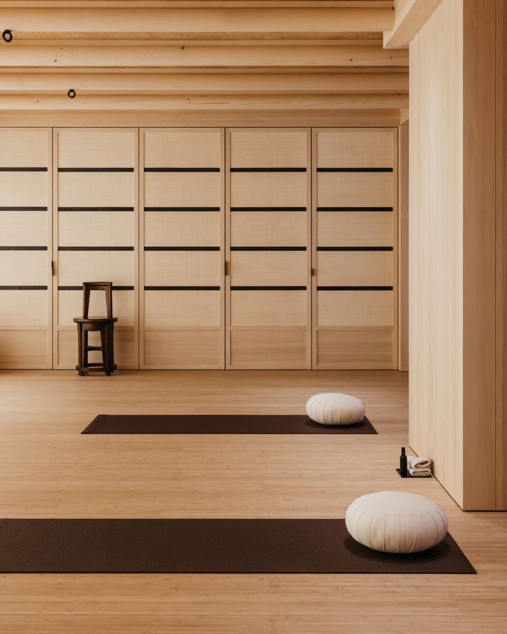 there are two white pillows on the floor in this room with yoga mats and stools