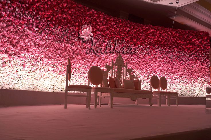 an artistic display with red flowers on the wall and benches in front of it,