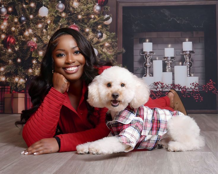 a woman posing with her dog in front of a christmas tree