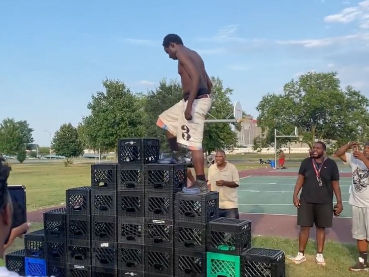 a man standing on top of black boxes in front of other men at a basketball court