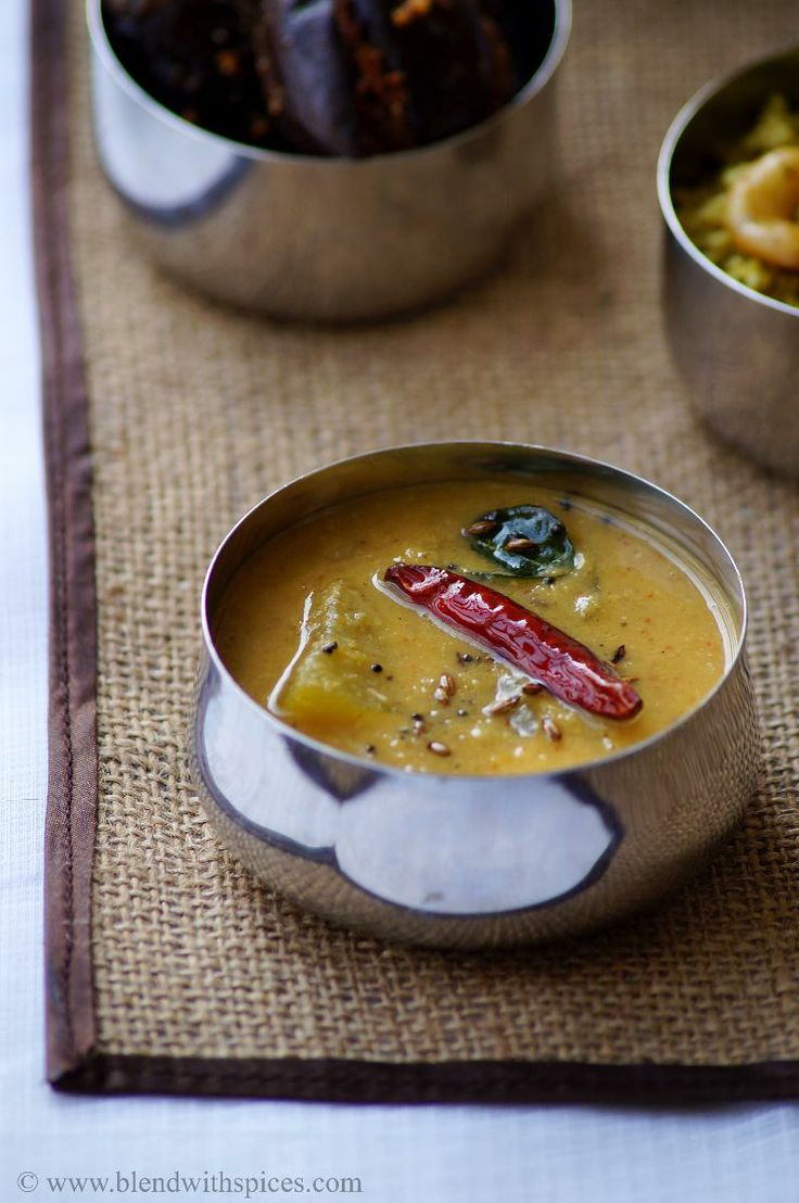 there is a bowl of soup on the table with other dishes around it, including bread and vegetables