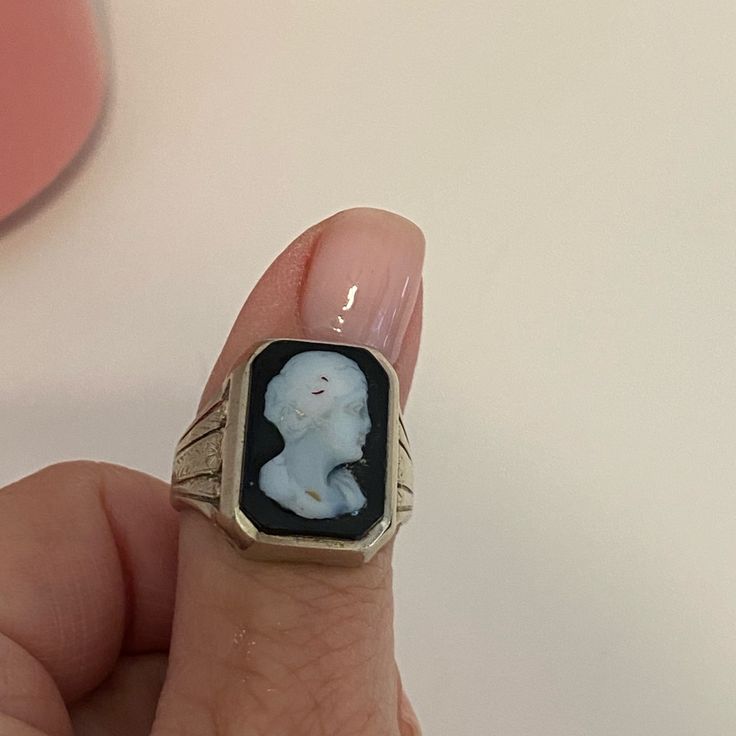 a woman's hand holding a ring with a small white dog on it