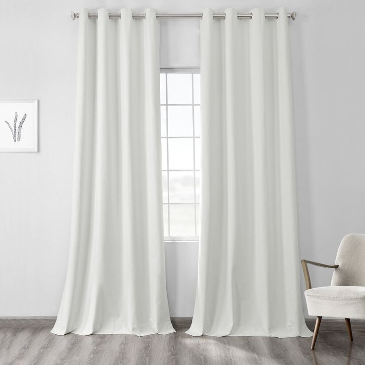 a white curtain hanging on the side of a wall next to a chair and window