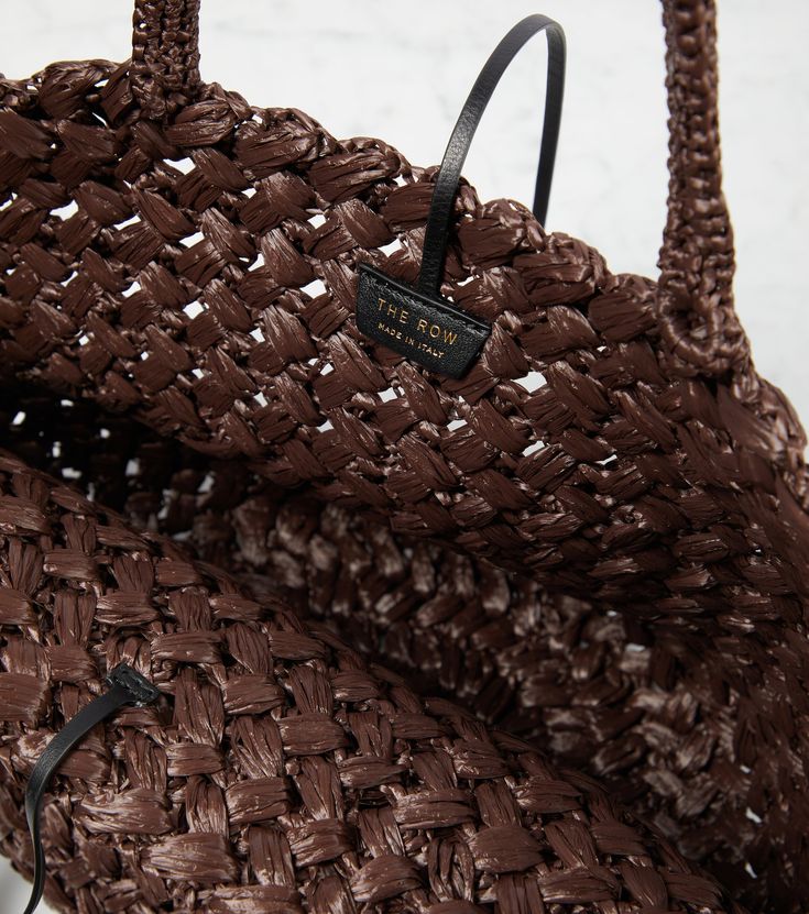 Estelle raffia tote bag in brown - The Row | Mytheresa Brown Luxury Woven Shoulder Bag, Luxury Brown Woven Shoulder Bag, Luxury Brown Woven Bag, Luxury Woven Bag With Double Handles, Chic Tan Woven Bags, Elegant Tan Bags With Braided Handles, Luxury Tan Shoulder Bag With Braided Handles, Luxury Woven Bags For Travel, Luxury Brown Shoulder Bag With Rolled Handles