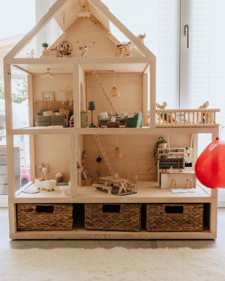 a wooden doll house with lots of furniture and accessories on display in front of a window