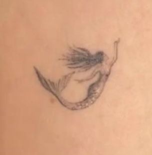 the back of a woman's stomach with a mermaid tattoo on it