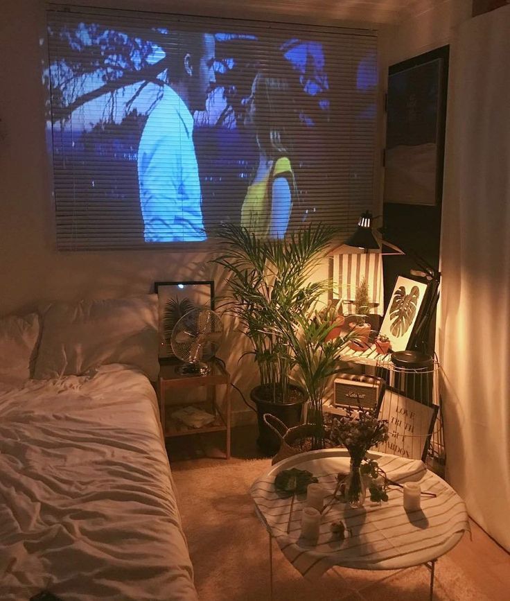 a bedroom with a large screen on the wall next to a bed and two planters