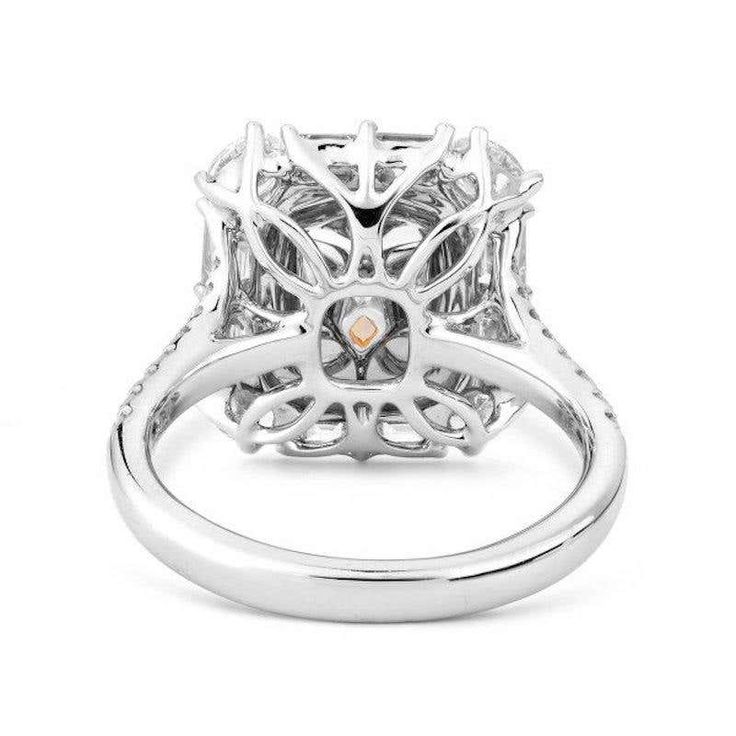 a white gold and diamond ring with an intricate design on the center, surrounded by small diamonds