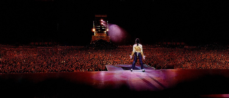 a man standing on top of a stage in front of an audience at a concert