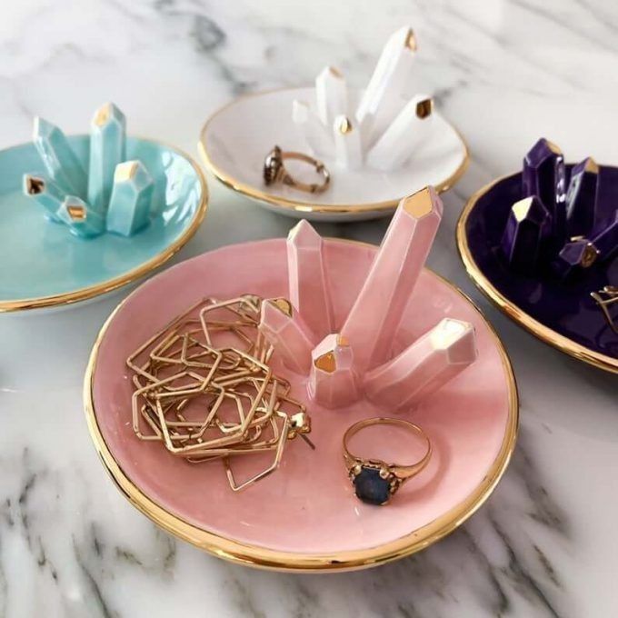 three different colored plates with gold rings and other items on them sitting on a marble surface