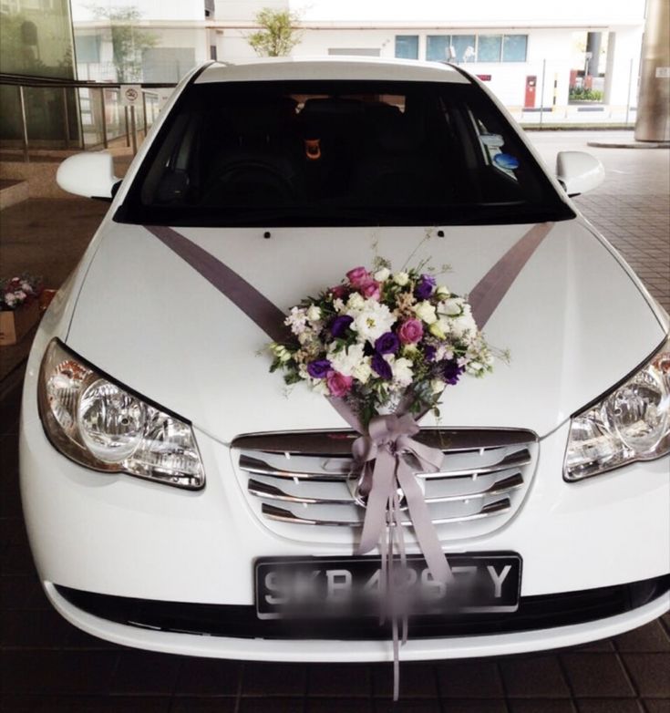 a bouquet of flowers is tied to the front of a white car