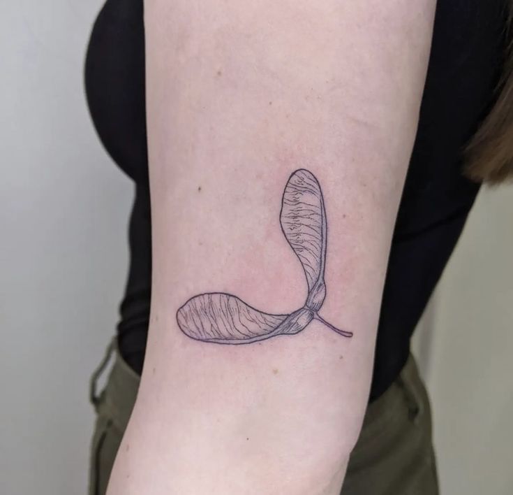 a woman's arm with a single line drawing of a leaf on the back of her left arm