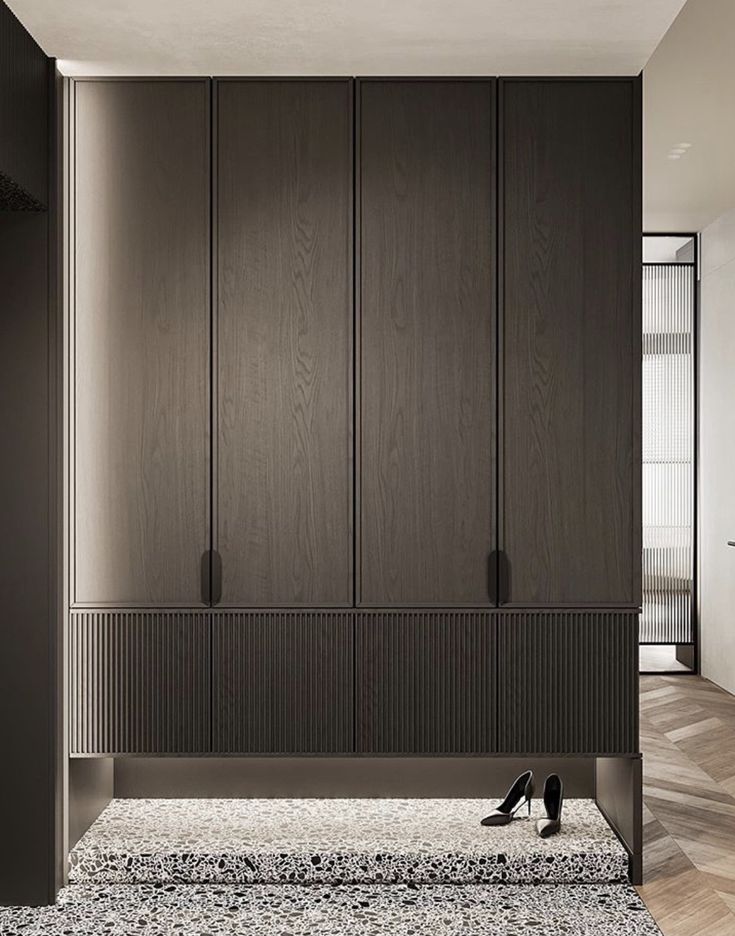 an empty room with dark wood cabinets and black shoes on the floor in front of it