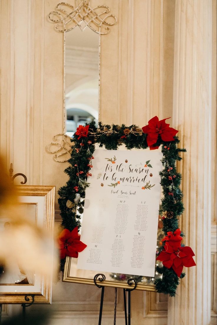 a sign that is sitting in front of a wall with christmas decorations on it and red poinsettis