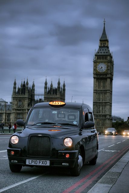 a taxi cab driving down the street in front of big ben