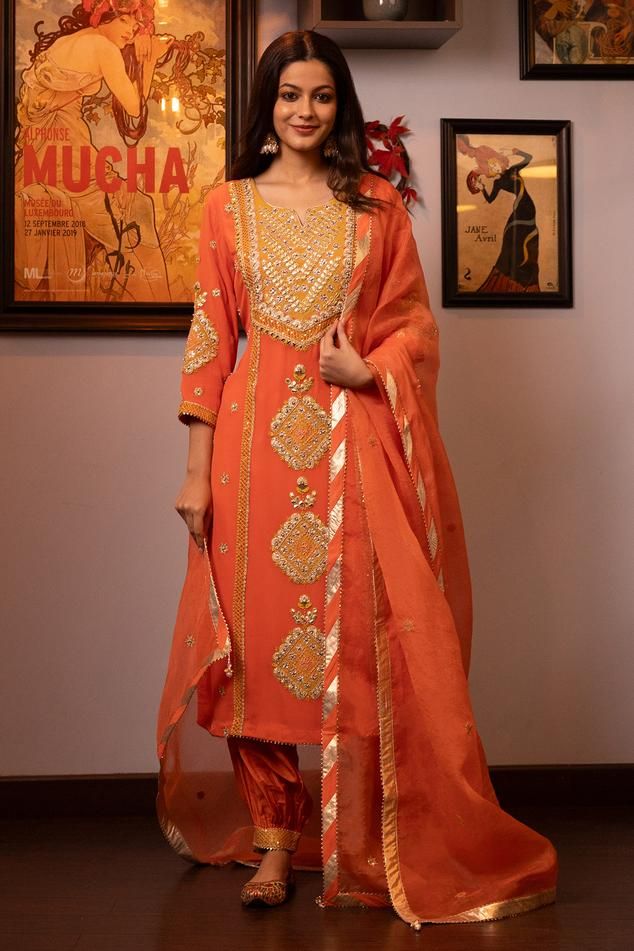 Saffron orange three fourth sleeves silk georgette bloom motif embroidered kurta with gota lace detailing. Paired with pleated hem pant and embroidered organza dupatta.
Components: 3
Pattern: Embroidery
Type Of Work: Bloom Motif
Neckline: Notched V
Sleeve Type: Three Fourth
Fabric: Kurta: Silk Georgette, Pant: Dupion, Dupatta: Organza
Color: Orange
Other Details: 
Attached inner lining
Weight: 1500 gms
Model Height: 5ft 7inches, wearing size M
Occasion: Sangeet, Mehendi and Haldi - Aza Fashions Embroidered Straight Kurta Anarkali Set In Orange, Orange Georgette Traditional Wear With Mirror Work, Elegant Orange Embroidered Sets, Elegant Embroidered Orange Sets, Orange Palazzo Set With Dabka Work And Straight Kurta, Designer Orange Sets With Chikankari Embroidery, Fitted Orange Kurta With Dabka Work, Festive Orange Unstitched Long Sleeve Suit, Festive Orange Sets With Chikankari Embroidery