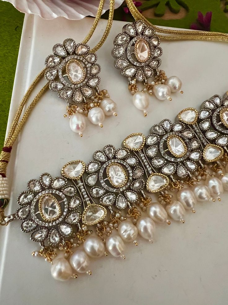 One of our favorite picks for the wedding season ♥️ The gorgeous choker is beautifully handcrafted by our skilled Indian craftsmen in Kundan stones, Ghungroo, mini pearls, and dual tone plated. The beautiful Kundan earrings add to the traditional ethnicity of the piece. Material: Brass with dual tone plating The length of the earrings is 5 cm. The width of the earrings is 3 cm. The weight of the earrings is 28 grams per pair. Elegant Dual-tone Kundan Necklace For Wedding, Elegant Dual-tone Kundan Necklace Gift, Silver Dual-tone Kundan Necklace For Wedding, Wedding Silver Dual-tone Kundan Necklace, Festive Silver Pearl Jewelry, Elegant Dual-tone Kundan Bridal Necklace, Elegant Kundan Dual-tone Bridal Necklace, Elegant Stone Work Choker For Gift, Dual-tone Bollywood Jewelry For Wedding