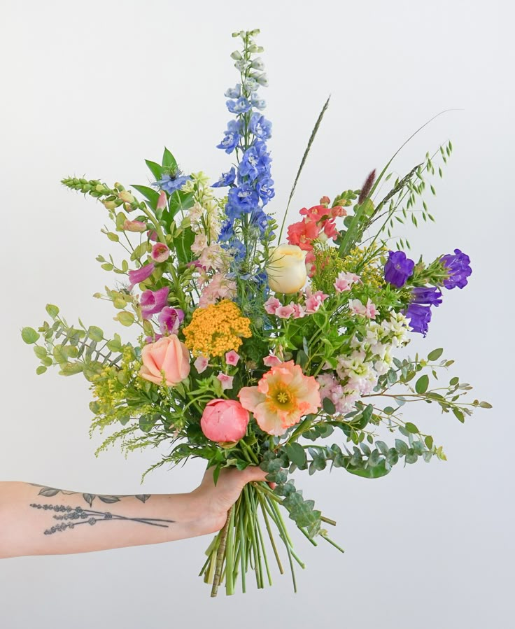 a person holding a bouquet of flowers in their left hand with tattoos on the arm