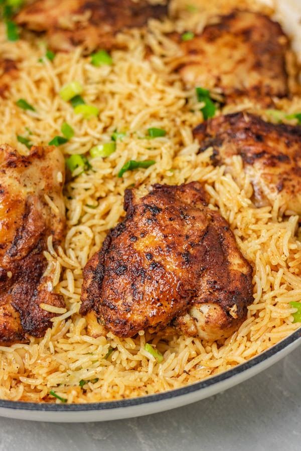 chicken and rice in a skillet with green onions on the side, ready to be eaten