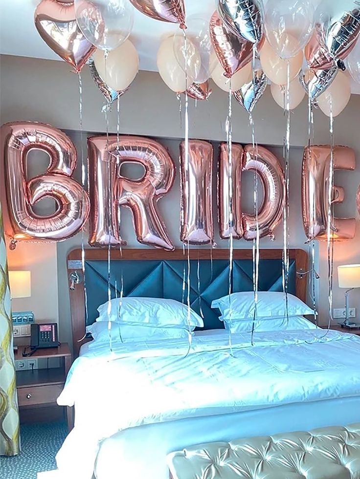 balloons are hanging from the ceiling above a bed in a room with a large headboard