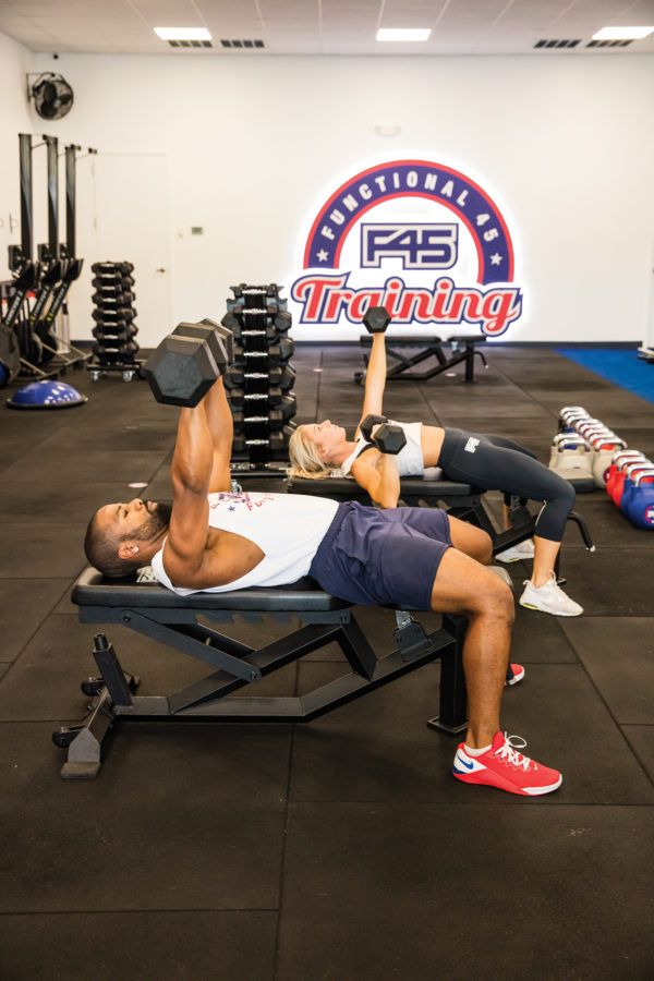 two people doing bench press in a gym