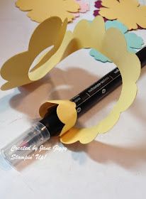 a close up of a pen on a table with paper cutouts and flowers in the background