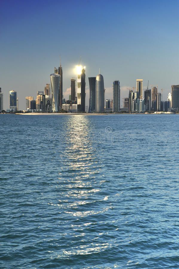 the city skyline is reflected in the water on a sunny day with blue sky and clouds