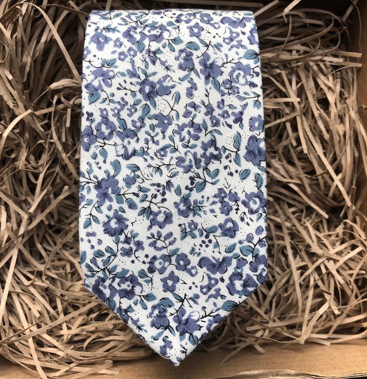 The Blue Scheherazade Floral Necktie in Cotton. This is a blue floral men's tie - perfect for weddings. We offer free shipping within the UK or a standard  WorldWide shipping cost of £3.99 to all countries outside of the UK. We also offer a free handwritten gift tag service - just leave the wording that you would like on the gift tag in the notes from buyer.  If you choose 'gift wrapping' we will send your item beautifully wrapped in a cardboard box with string and a gift tag with your message. We can also make all of our ties in children's sizes. Dimensions of tie: Tie width: 6cm   Tie length: 147cm   Also available in 8cm wide tie We offer a set of pre-made ties and pocket squares. The full set comprises of a bow tie, necktie and pocket square or each item can be bought individually. Our Blue Standard Tie For Wedding, Blue Suit And Tie Accessories For Wedding, Blue Summer Wedding Ties, Blue Ties For Wedding Neckwear, Blue Tie For Black Tie Event And Father's Day, Blue Standard Tie For Father's Day, Blue Ties For Father's Day, Blue Wedding Neckwear With Ties, Summer Ties For Groom