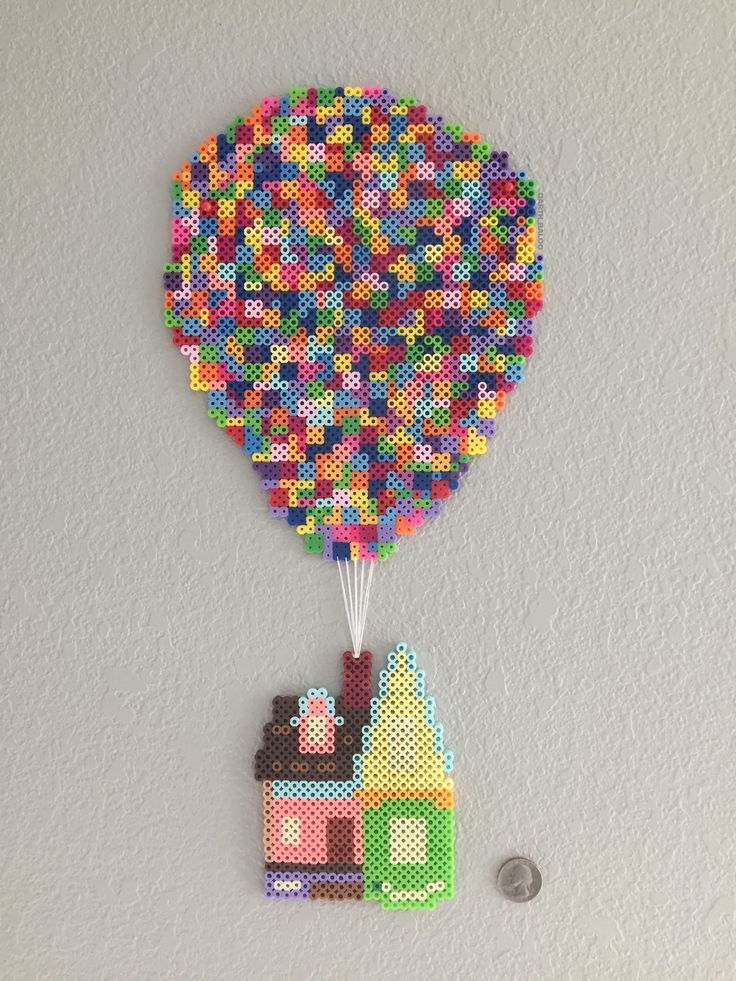 a colorful hot air balloon is hanging on the wall next to a small house made out of legos