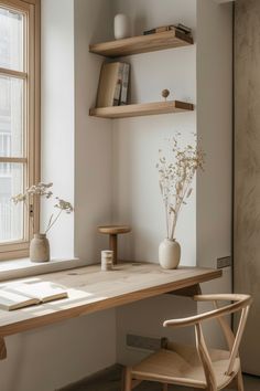 a wooden desk sitting in front of a window next to a vase with flowers on it