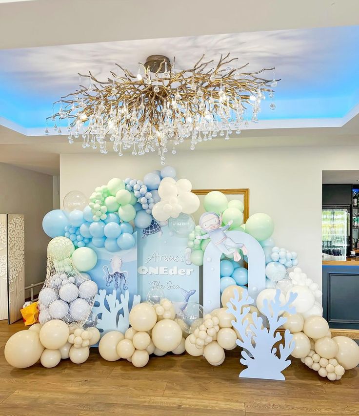 a room with balloons and decorations on the floor in front of a chandelier