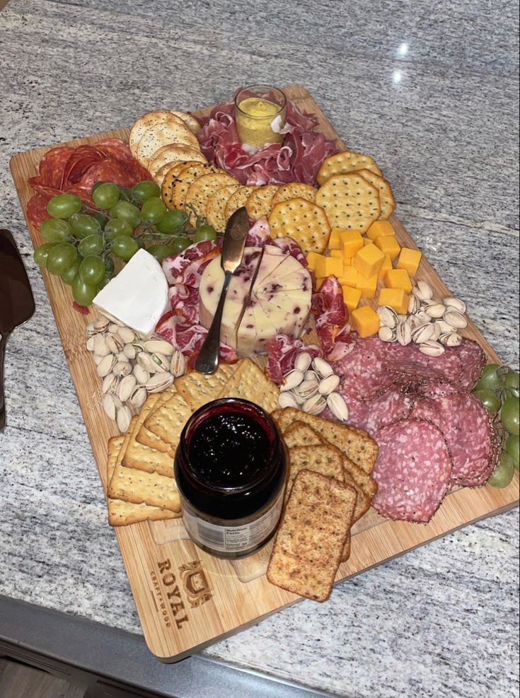 a wooden platter filled with cheese, crackers and meats