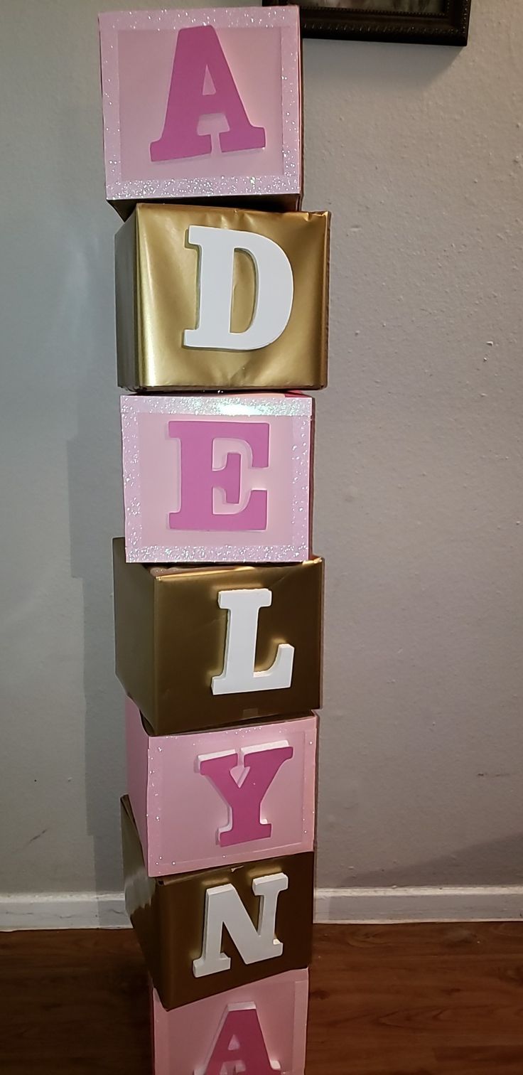 three pink and gold blocks with letters that spell out the word adel, yn