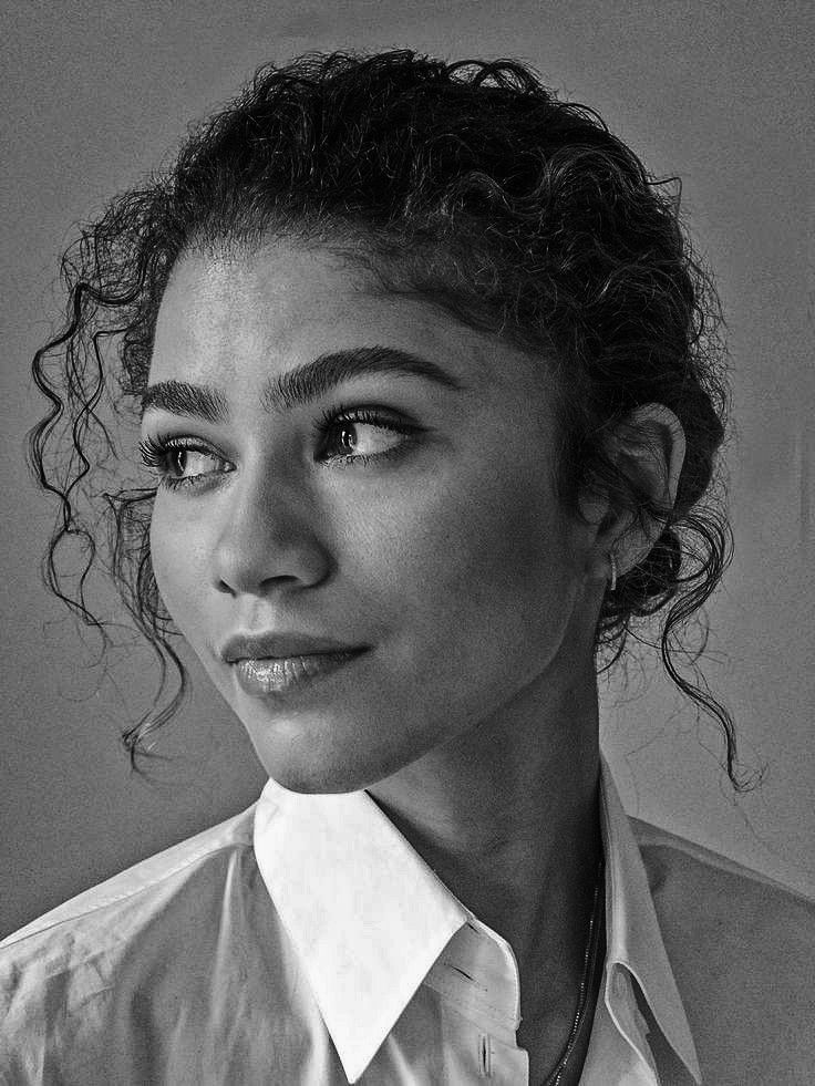 a black and white photo of a woman with curly hair wearing a collared shirt