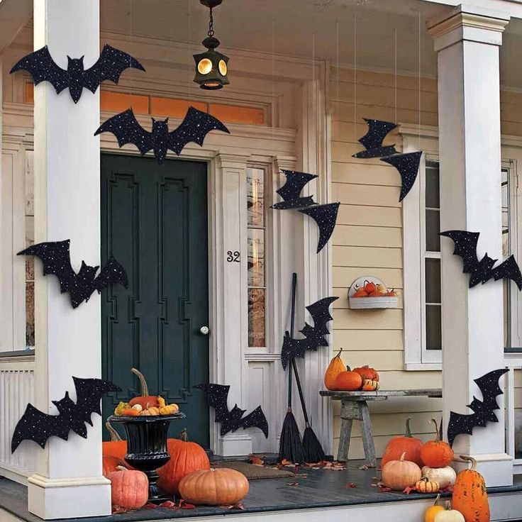 a porch decorated for halloween with bats and pumpkins